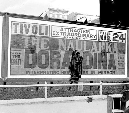 1918 Doraldina standing in front of a billboard for Naulahka